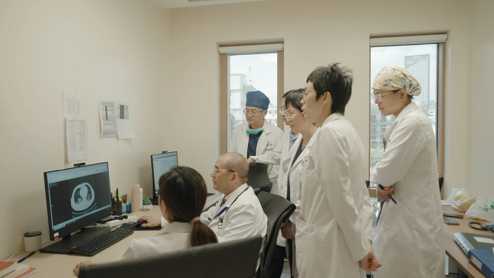 SinoUnited Health hematology and oncology clinicians reviewing a patient's scan together on screen in Shanghai.