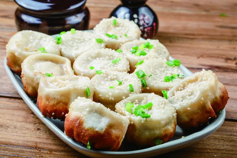 Pan-fried buns topped with sesame and spring onion