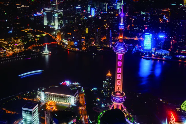 The Pudong skyline and Oriental Pearl Tower lit at night, across the Huangpu River